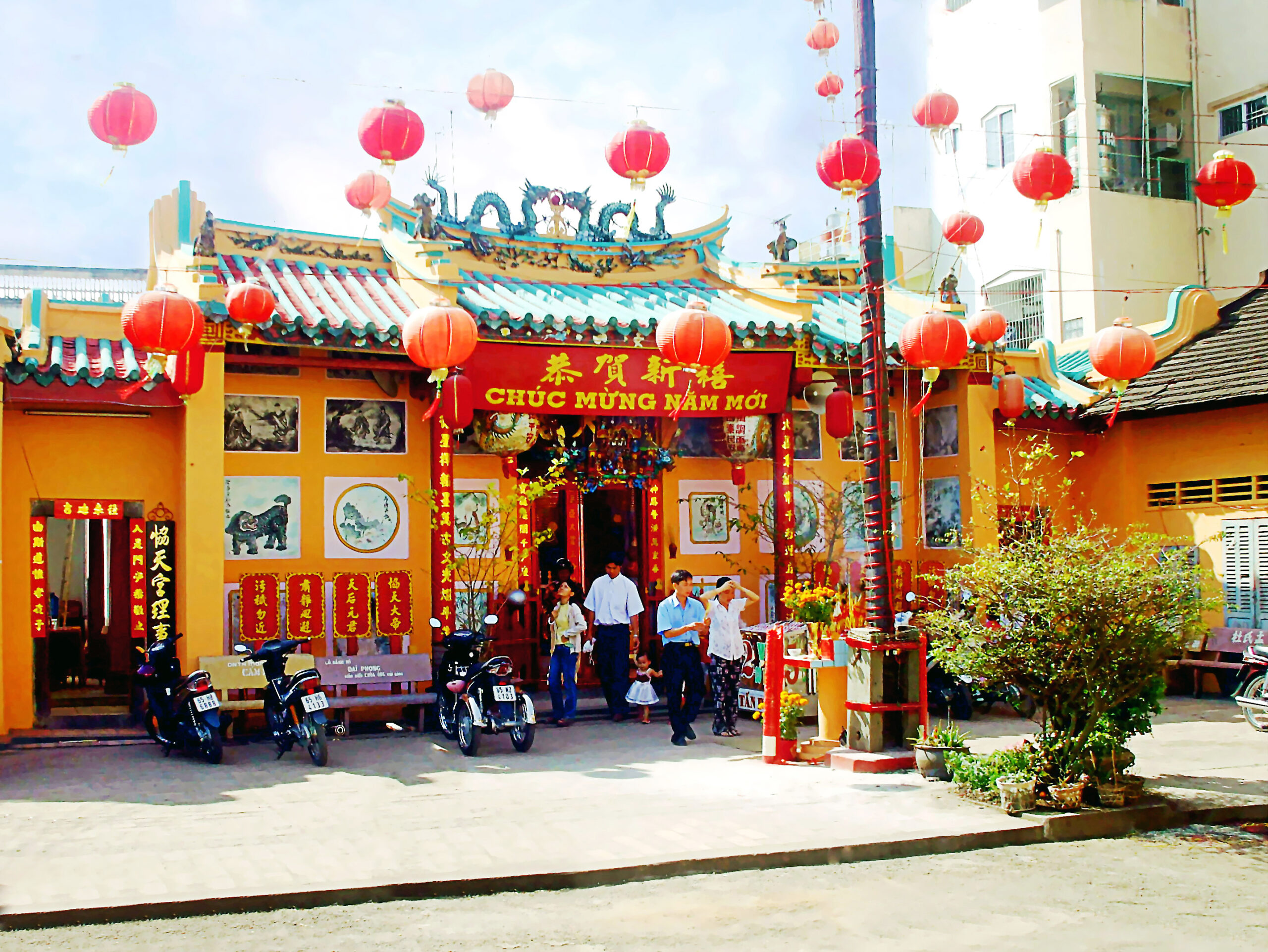 Cette image représente la pagode Hiệp Thiên Cung, un temple chinois traditionnel situé dans le delta du Mékong, au Vietnam. Le temple est magnifiquement décoré de lanternes rouges et de bannières festives célébrant le Nouvel An lunaire. On peut y voir des visiteurs et des familles locales entrer pour prier et profiter de l'atmosphère festive. L'architecture colorée, les toitures traditionnelles et les décorations de lanternes témoignent de la forte influence culturelle de la communauté sino-vietnamienne du sud du Vietnam. Hiệp Thiên Cung est un site spirituel et culturel important qui attire aussi bien les locaux que les voyageurs internationaux explorant le delta du Mékong.